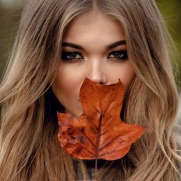 Image of a woman holding a vibrant fall leaf. 
