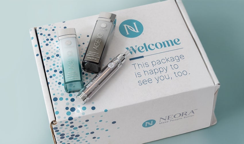 A Neora packaging box with various Neora skincare products on top.