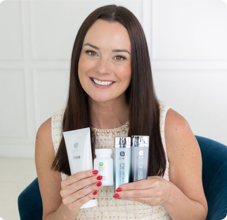 Amber Olson Rourke smiling while holding various Neora skincare products.