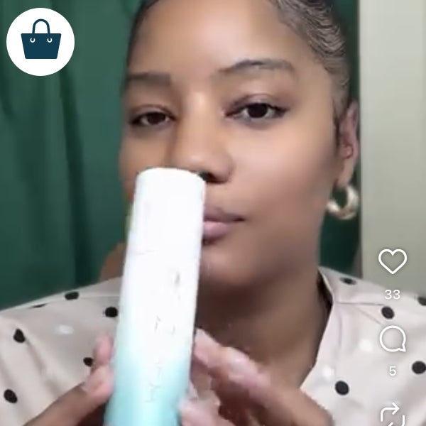 A woman holding a bottle of Neora’s Instant Facial.