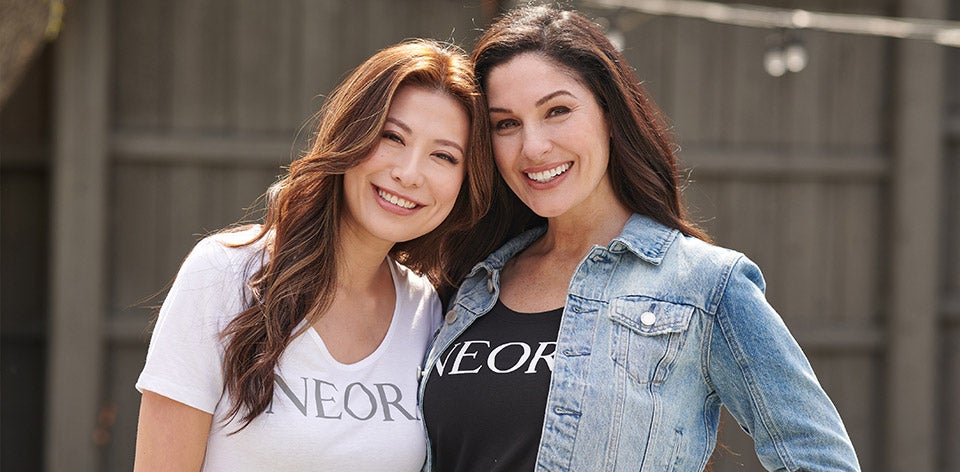 Two Neora Brand Partners wearing Neora apparel standing next to each other outside.