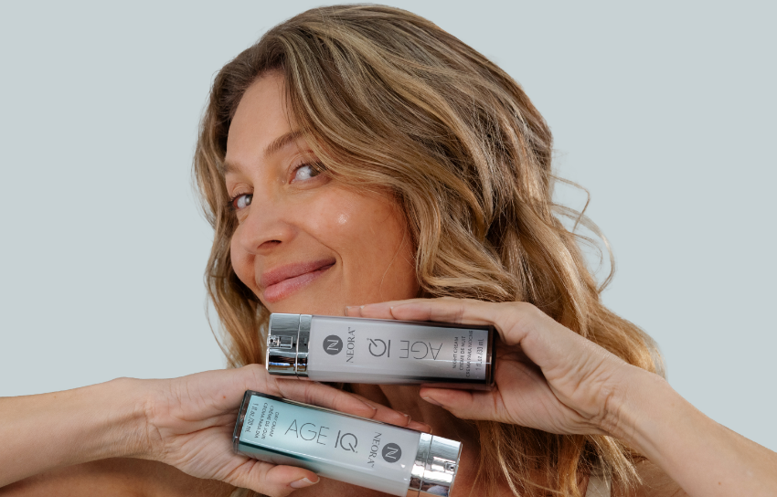 A woman holding a pair of Age IQ Day & Night Cream bottles to her face.