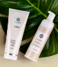 A bottle of Neora’s Firm Body Contour Cream and Sunless Tanner on a leaf.