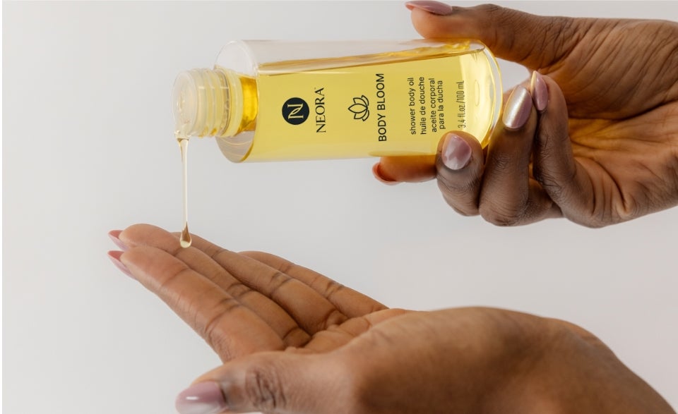A woman pouring Body Bloom oil onto her hand.
