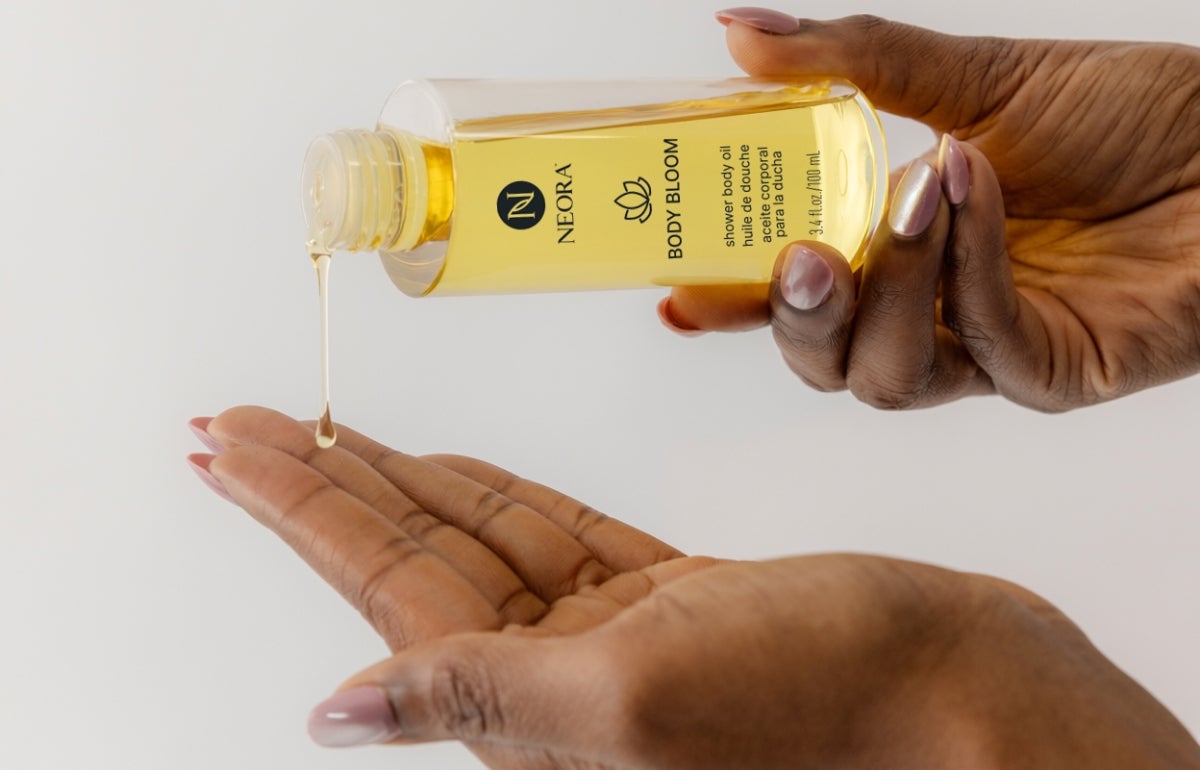 A woman pouring Body Bloom oil onto her hand.