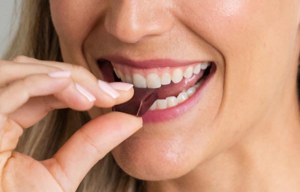 A woman biting into a Energy+ Wellness Chew.