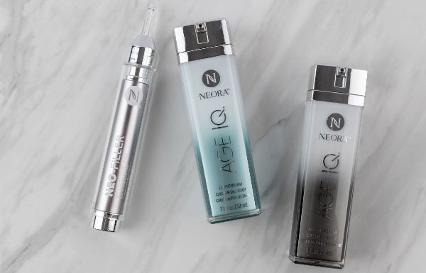 Bottles of Age IQ Day Cream, Age IQ Night Cream, and Neo-Filler spread out on a marble counter.