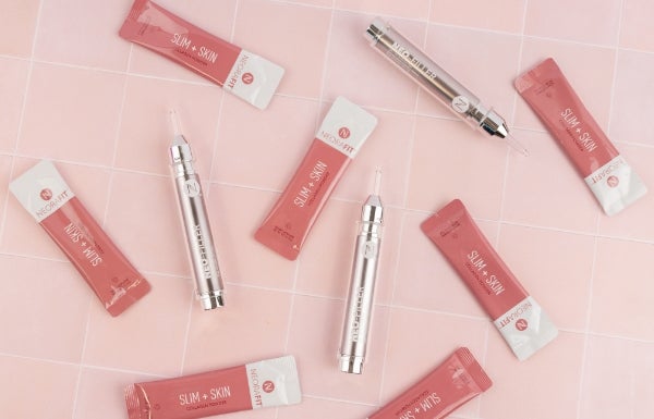 Various sachets of NeoraFit Slim + Skin & Neo-FILLER tubes arranged on a pink tile background.