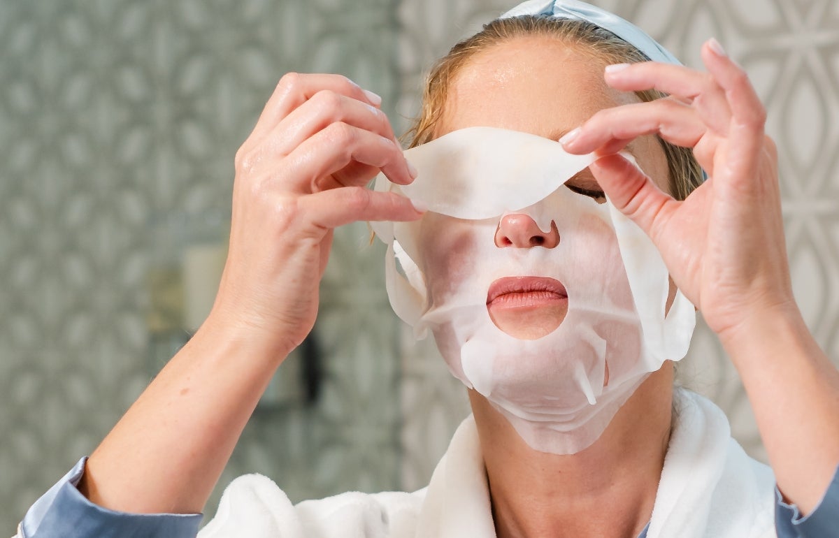 A woman applying a Marine Collagen Sheet Mask to her face.