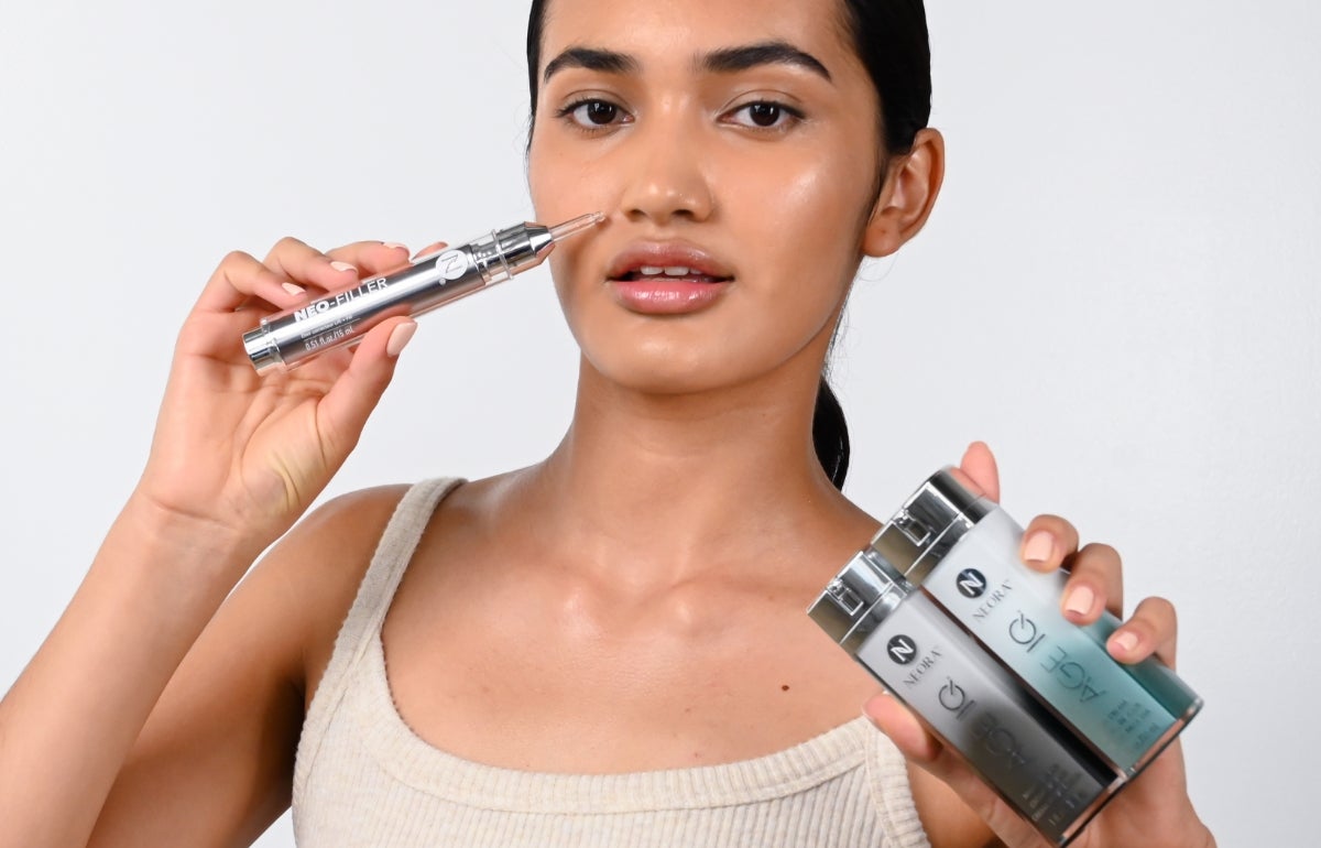 A woman holding a tube of Neo-FILLER to her face in one hand and Age IQ Day & Night Creams in the other hand.