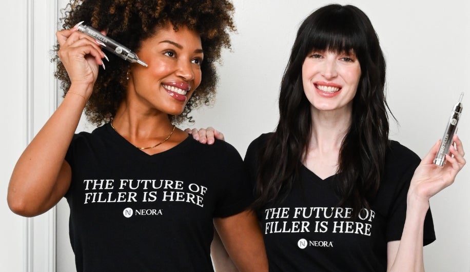 Two women wearing black T-shirts that read “The Future of Filler Is Here” smiling while holding Neo-FILLER, standing side by side against a light background.