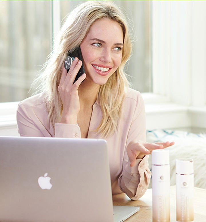 Un Socio de Marca de Neora está trabajando en su negocio desde casa en su computadora portátil, educando a un cliente potencial sobre los muchos beneficios del Sistema de Cuidado del Cabello ProLuxe.