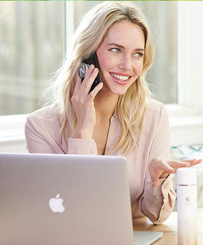 Un Socio de Marca de Neora está trabajando en su negocio desde casa en su computadora portátil, educando a un cliente potencial sobre los muchos beneficios del Sistema de Cuidado del Cabello ProLuxe.