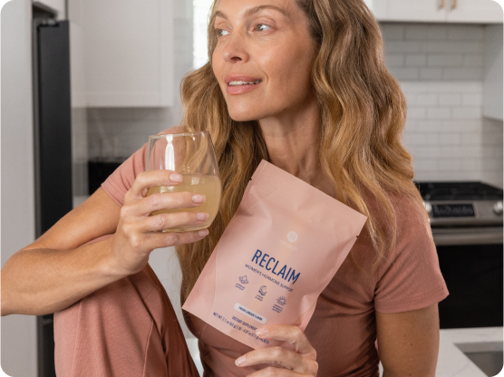 A woman holding a bag of RECLAIM™ and a drinking glass.