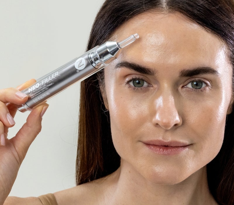 A woman holds up Neora’s Neo-FIller to her forehead.