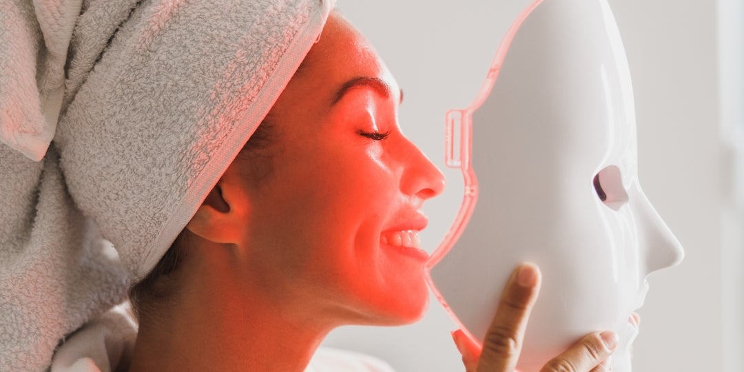 A woman using a red light mask.