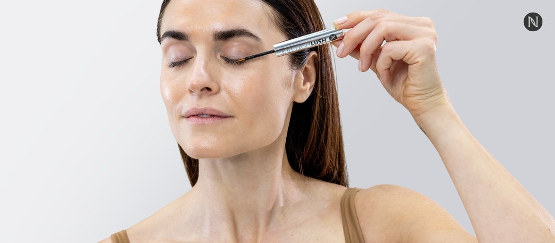 A woman applying Neora's LashLush to her eyelashes.