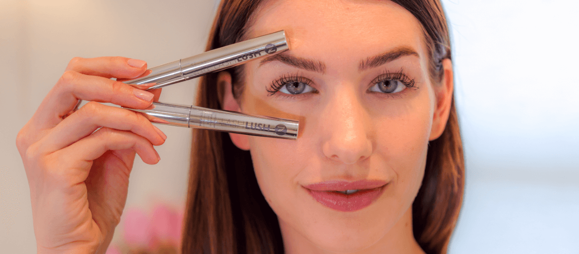 A woman holding two LashLush tubes to her face.