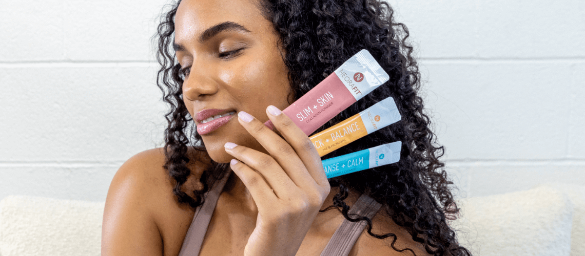 A woman holding NeoraFit sachets next to her face.