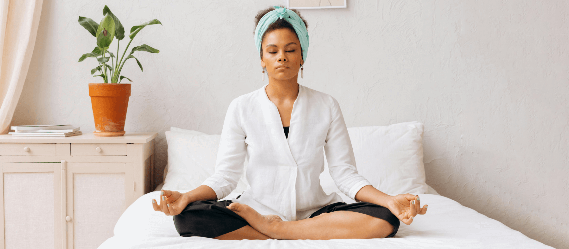 A woman meditating in her bed.