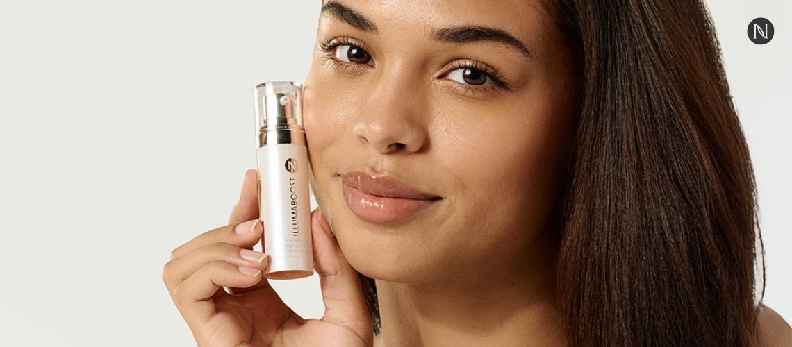 A woman holding a bottle of IllumaBoost.