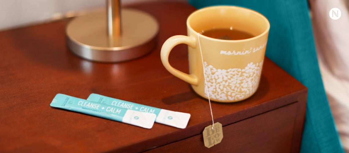 A mug filled NeoraFit Cleanse & Calm next to a couple of sachets.