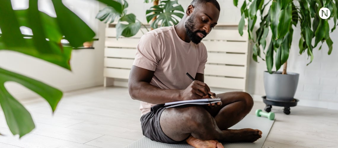 A seated man writing in his journal.