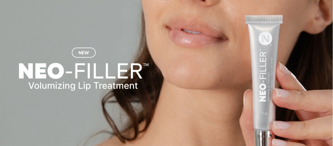 Close-up of a woman's lips as she holds a silver NEO-FILLER Volumizing Lip Treatment tube