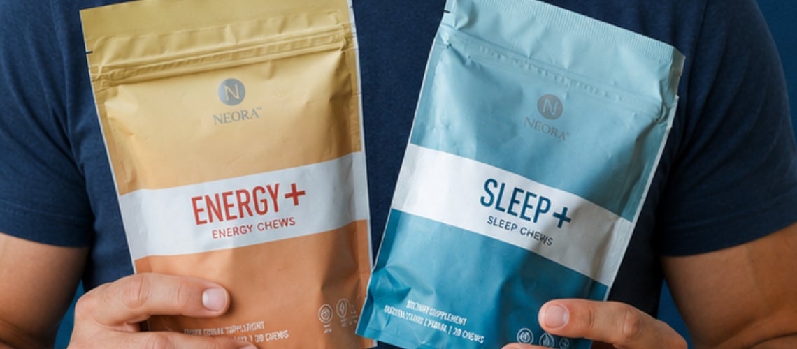 Two Neora pouches—Energy+ (orange) and Sleep+ (blue)—held by a person in a navy shirt.