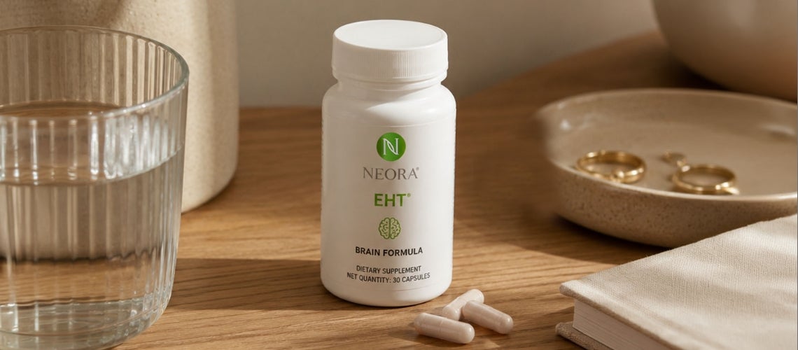 Bottle of Neora EHT Brain Formula dietary supplement on a wooden table with a glass of water nearby and a jewelry dish in the background.