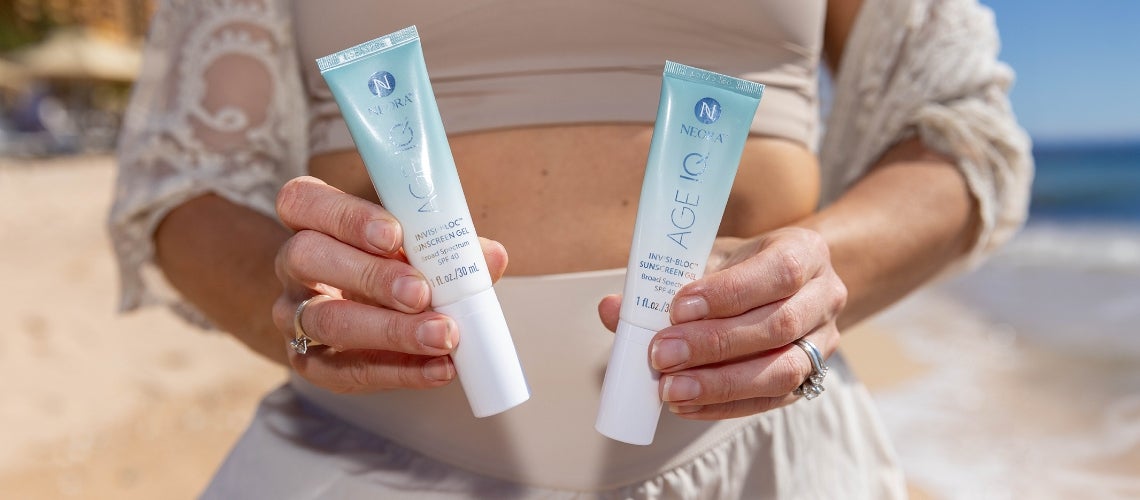 A woman holding up two tubes of Invisi-bloc SPF.