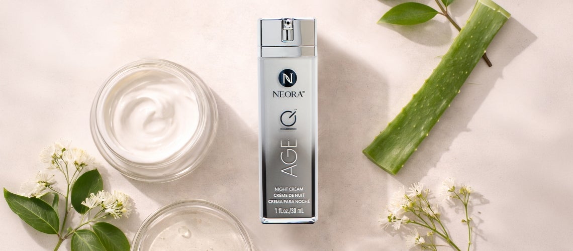 NEORA Age C Night Cream bottle on a beige surface, with two glass jars of cream, an aloe stem, and small white flowers.