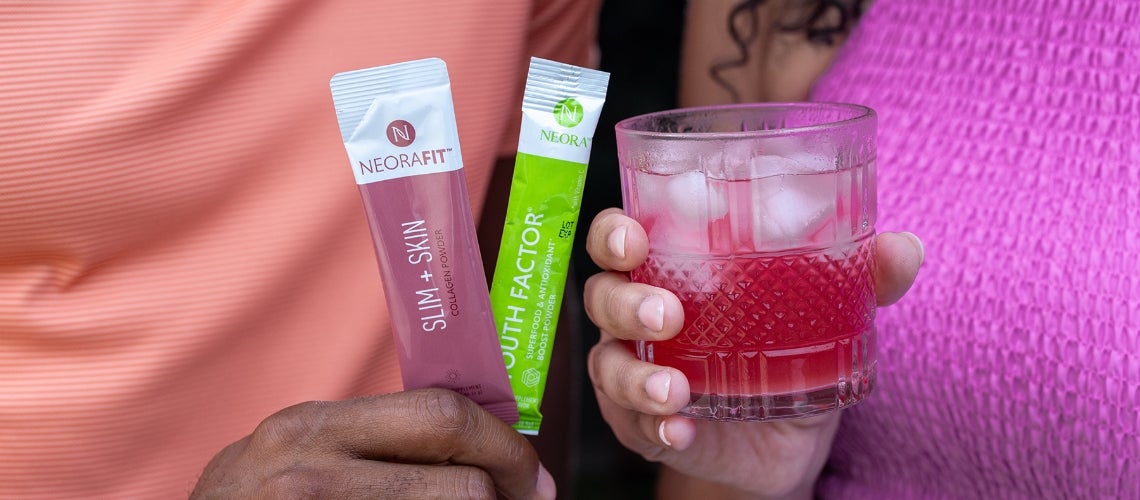 Two NeoraFit supplement sachets held beside a pink drink in a textured glass.