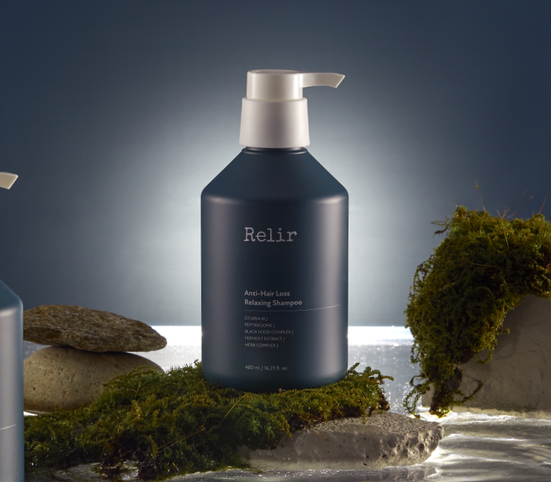 Neora’s professional-grade ProLuxe Rebalancing Shampoo sitting on a bathroom countertop in front of a mirror, plant and towel