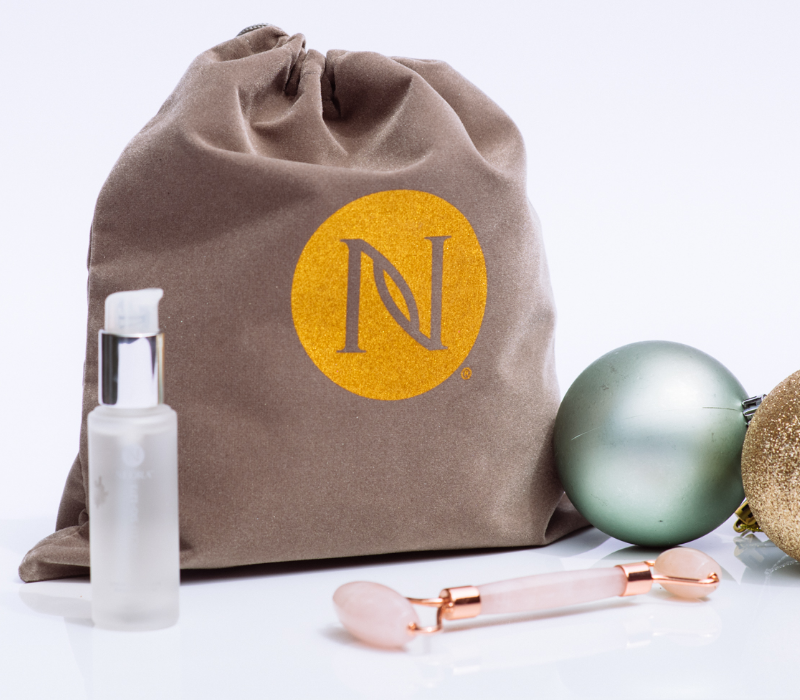 Neora’s hottest holiday must-have, the Radiance Gift Set, which includes Advanced SIG-1273 Concentrated Serum, FREE Rose Quartz Facial Roller and FREE Gift Bag surrounded by Christmas ornaments with a Black Friday Steal callout that this set is 15% off now through November 28*.