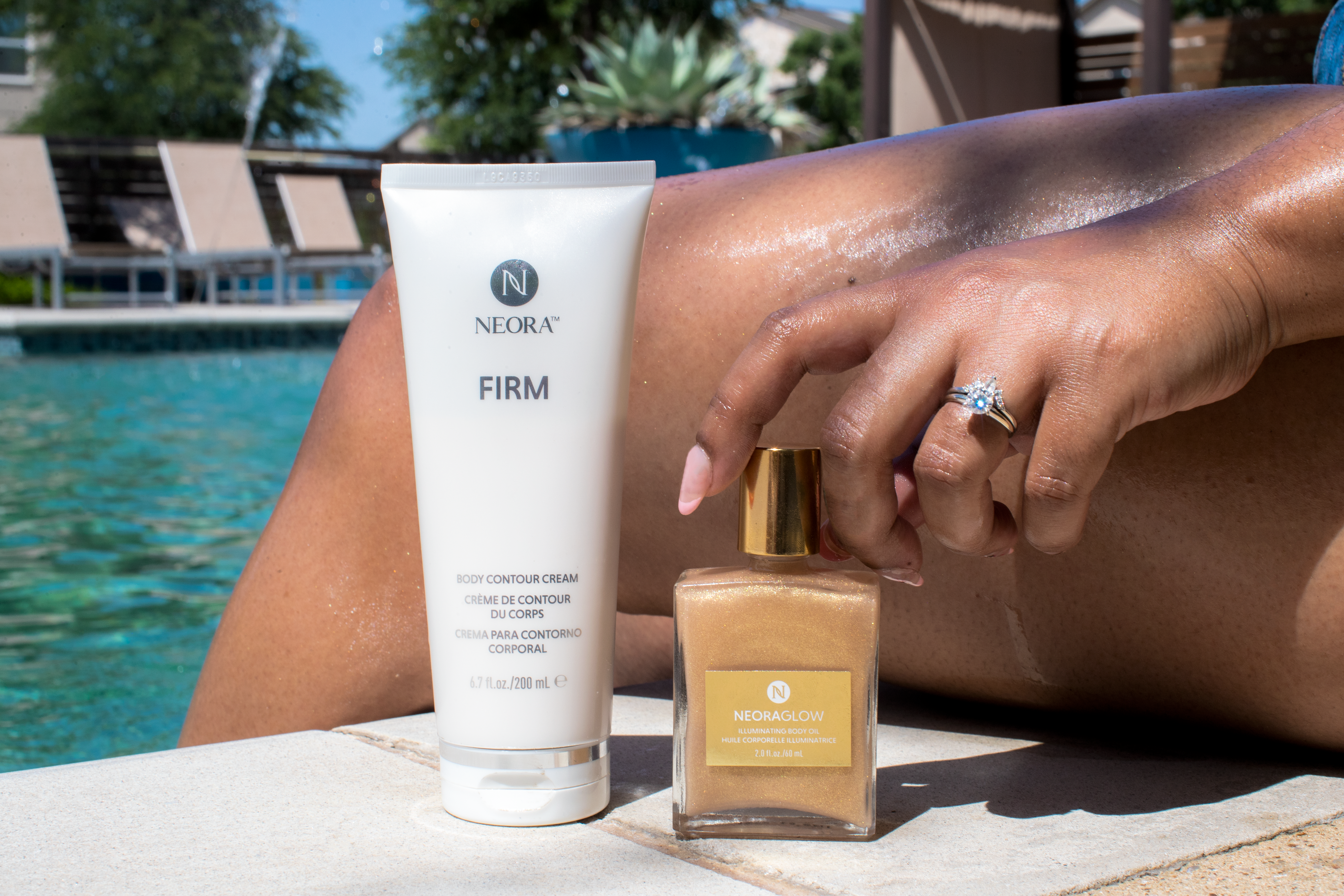 Neora’s Firm & Glow Summer Set sitting next to a pool. Set includes Firm Body Contour Cream and NeoraGlow Illuminating Body.]