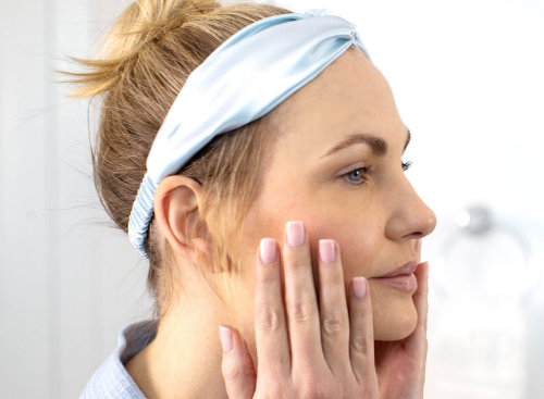  A close-up of a smiling woman’s face holding the SIG-1723 concentrated serum.