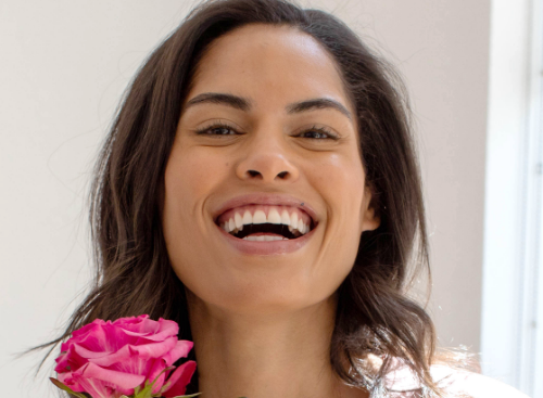 A close-up of a smiling woman’s face holding the SIG-1723 concentrated serum.