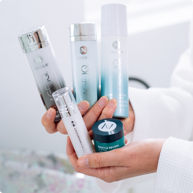 TWoman holding Neora’s hottest holiday must-have, the Clean Skin Set, which includes Age IQ Day and Night Cream, Age IQ Double-Cleansing Face Wash, IllumaBoost Brightening & Shield, Sequined Cosmetic Bag and FREE Gentle Reveal Lip Scrub.