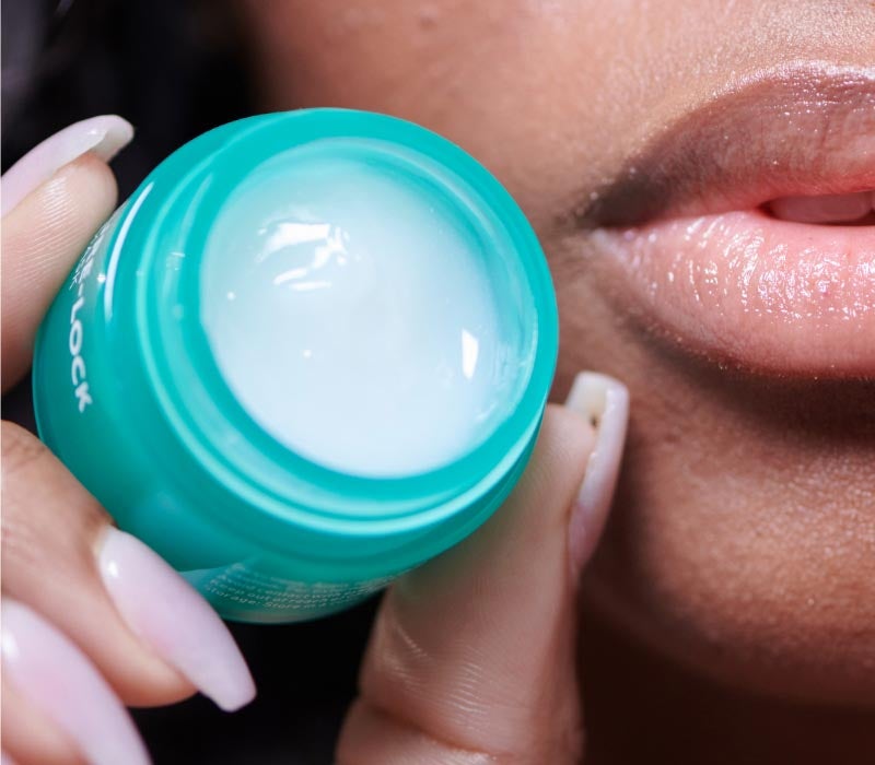 Mujer sosteniendo el producto de la Hot List de Neora, Moisture Lock Mascarilla labial, en la mano junto a los labios